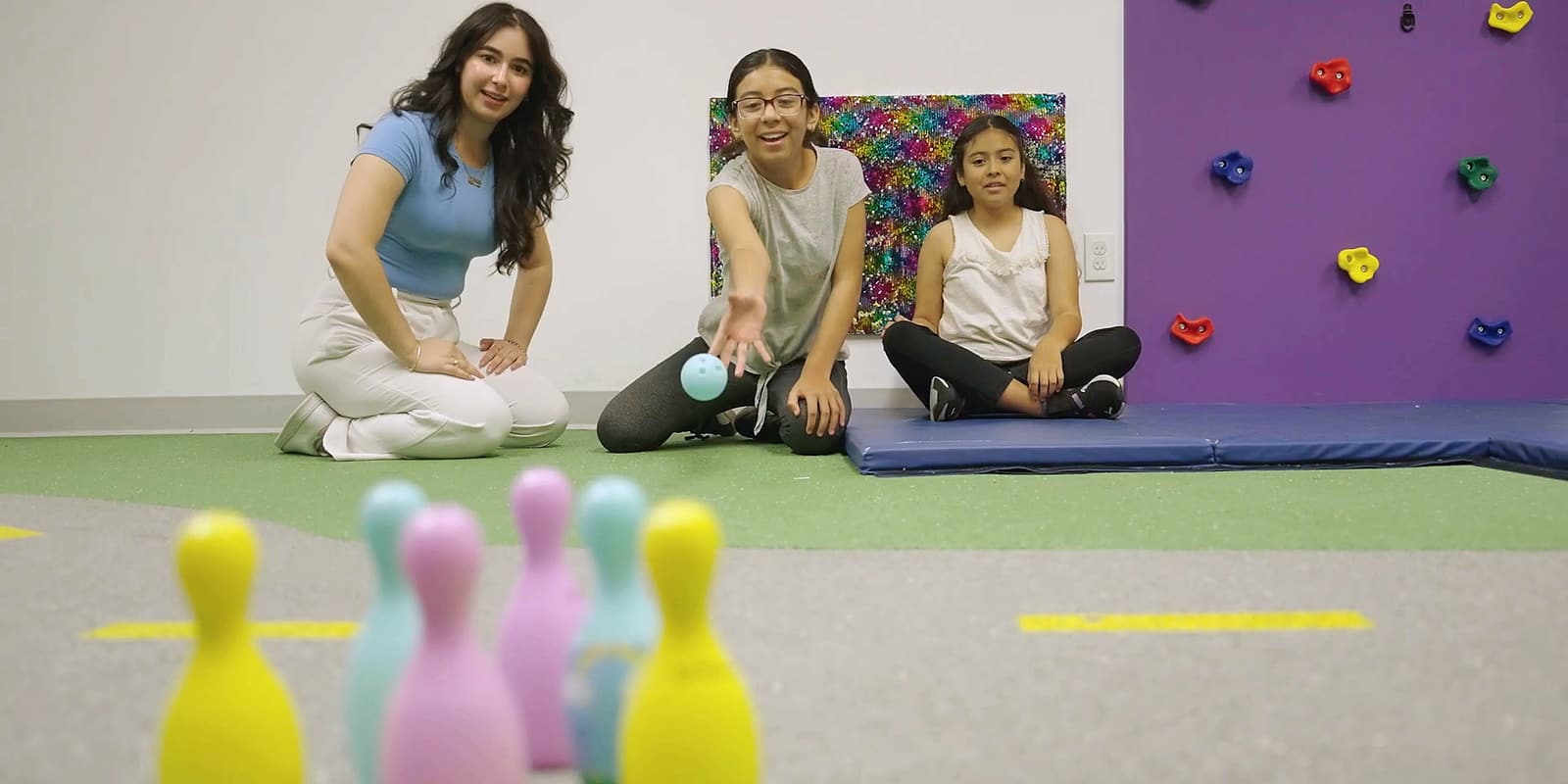 A therapist and two children playing a bowling game