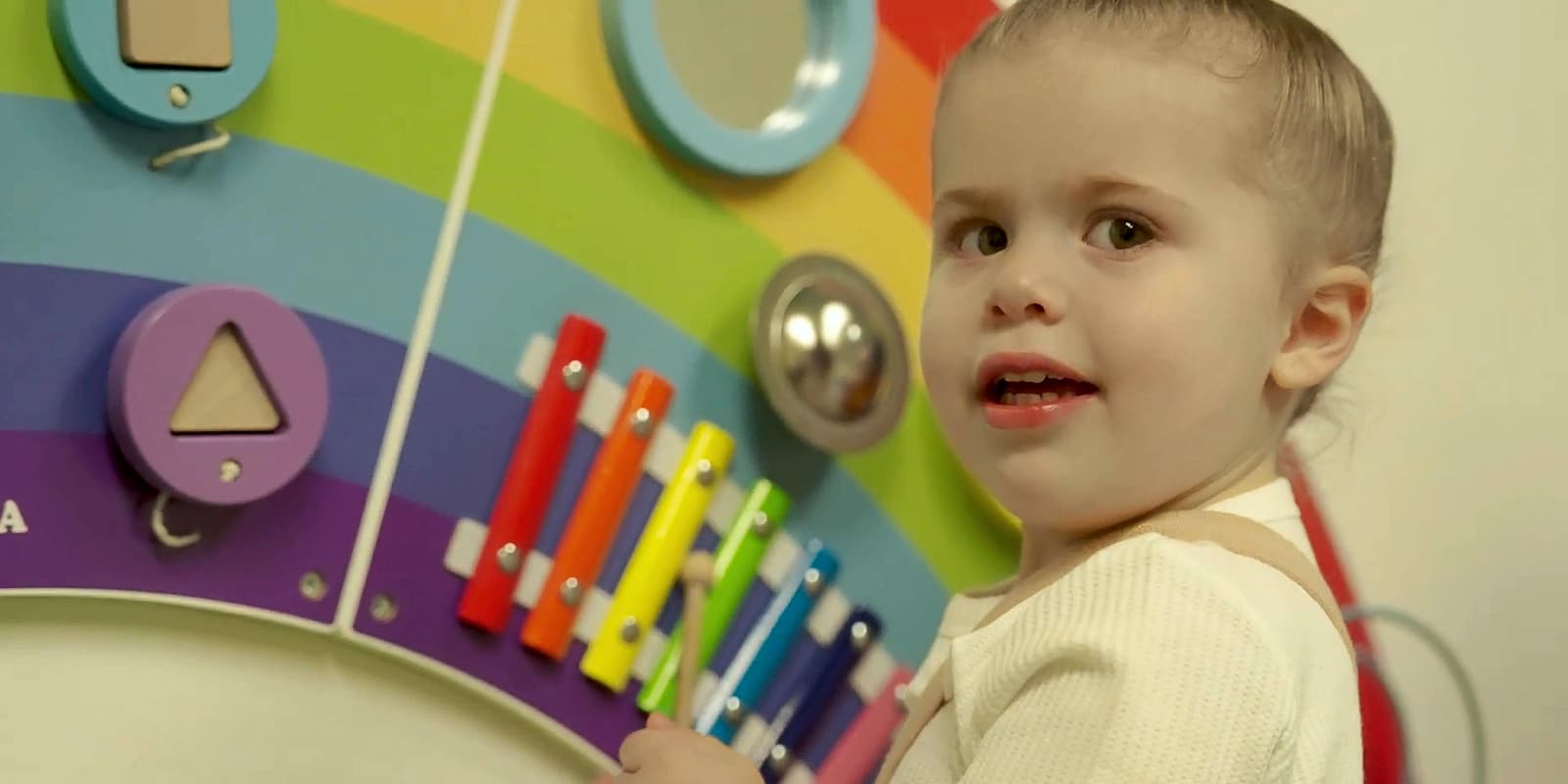 A toddler playing with a rainbow activity board