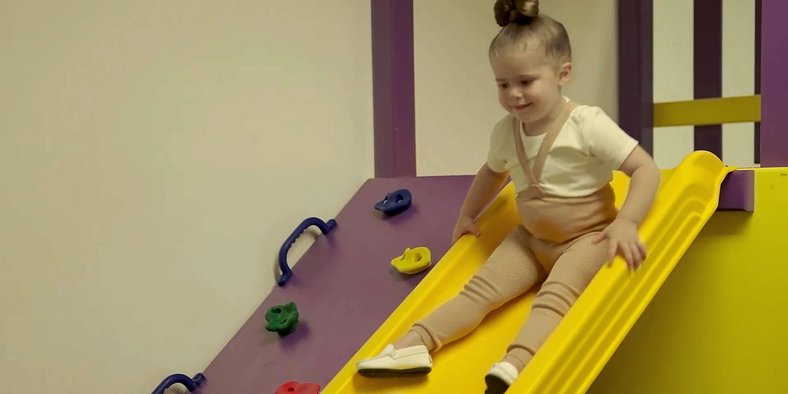 A toddler going down a slide in the sensory room